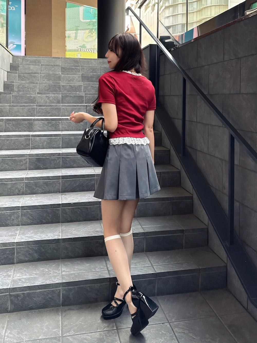 レッド系のTシャツ/カットソー、グレー系のスカート、ブラック系のハンドバッグを着用したレディースの夏コーディネートの4枚目の写真