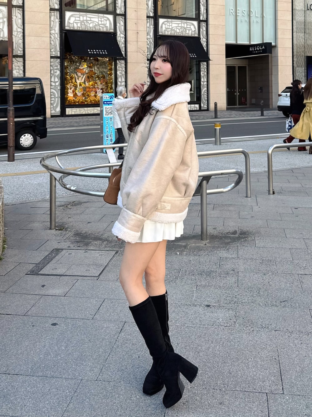 ホワイト系のブルゾン、ホワイト系のスカート、イエロー系のハンドバッグを着用したレディースの秋コーディネートの2枚目の写真