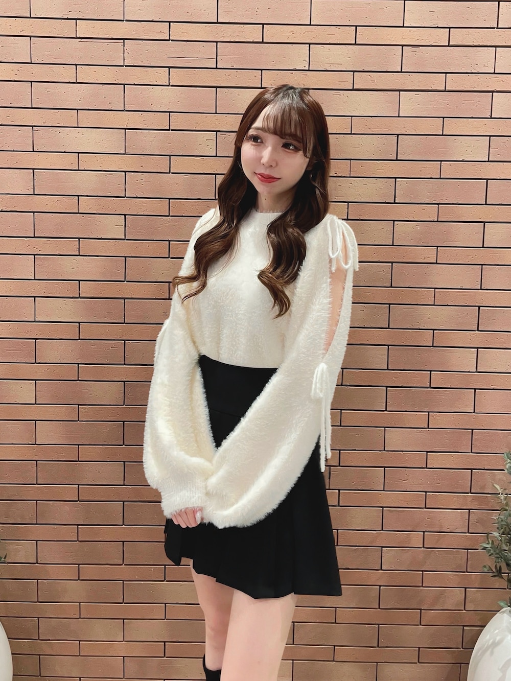 ホワイト系のニット/セーター、ブラック系のスカートを着用したレディースの秋コーディネートの2枚目の写真