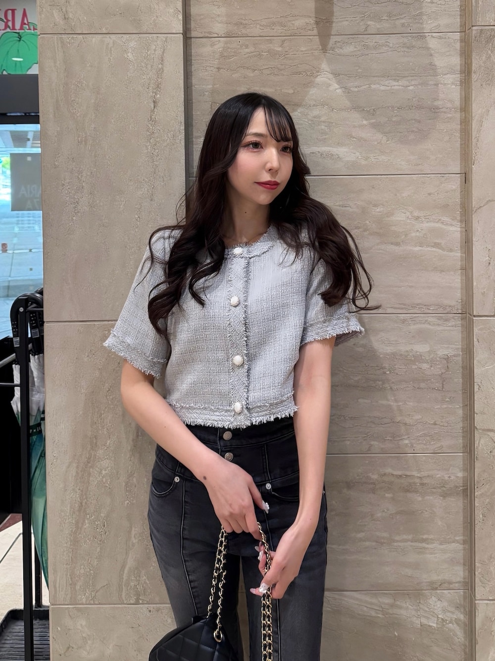 グレー系のノーカラージャケット、ブルー系のデニムパンツ、ブラック系のショルダーバッグを着用したレディースの春コーディネートの3枚目の写真