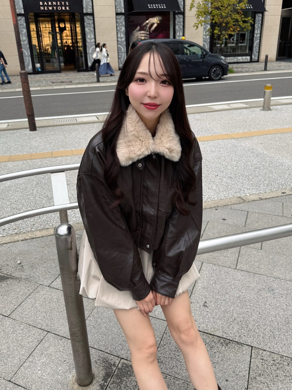 ブラック系のブルゾン、ベージュ系のスカート、ブラウン系のブーツを着用したレディースの秋コーディネートの6枚目の写真