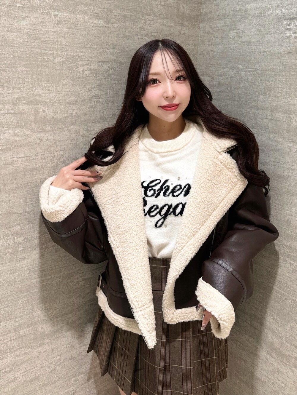 ブラウン系のムートンコート、ホワイト系のニット/セーター、ブラウン系のスカートを着用したレディースの秋コーディネートの5枚目の写真