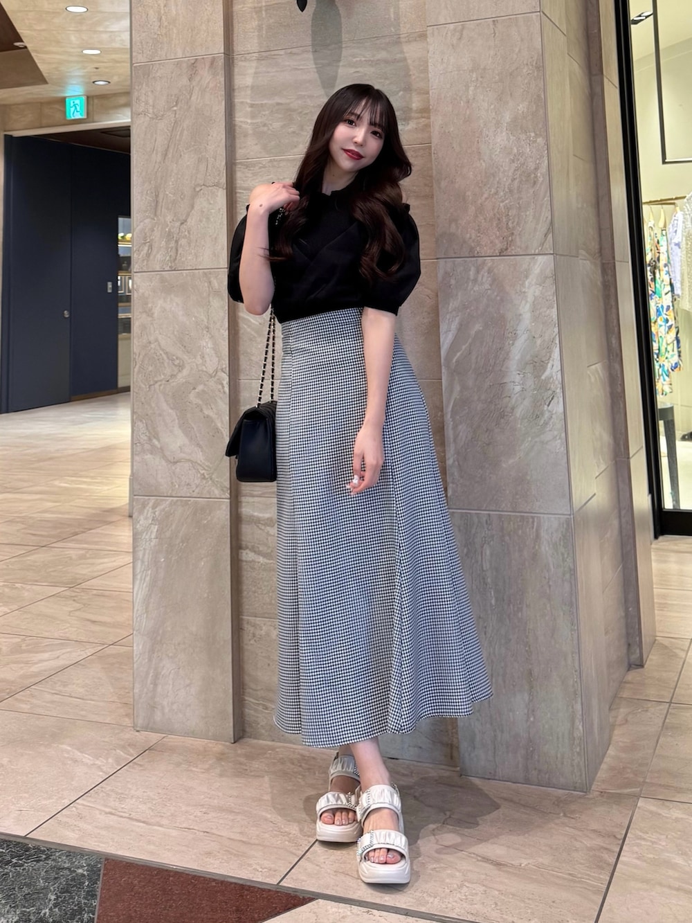 ブラック系のニット/セーター、ブラック系のスカート、ホワイト系のサンダルを着用したレディースの春コーディネートの2枚目の写真