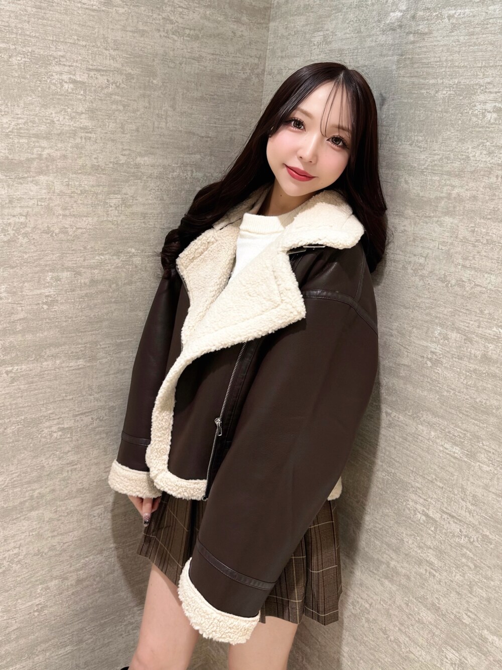 ブラウン系のムートンコート、ホワイト系のニット/セーター、ブラウン系のスカートを着用したレディースの秋コーディネートの6枚目の写真