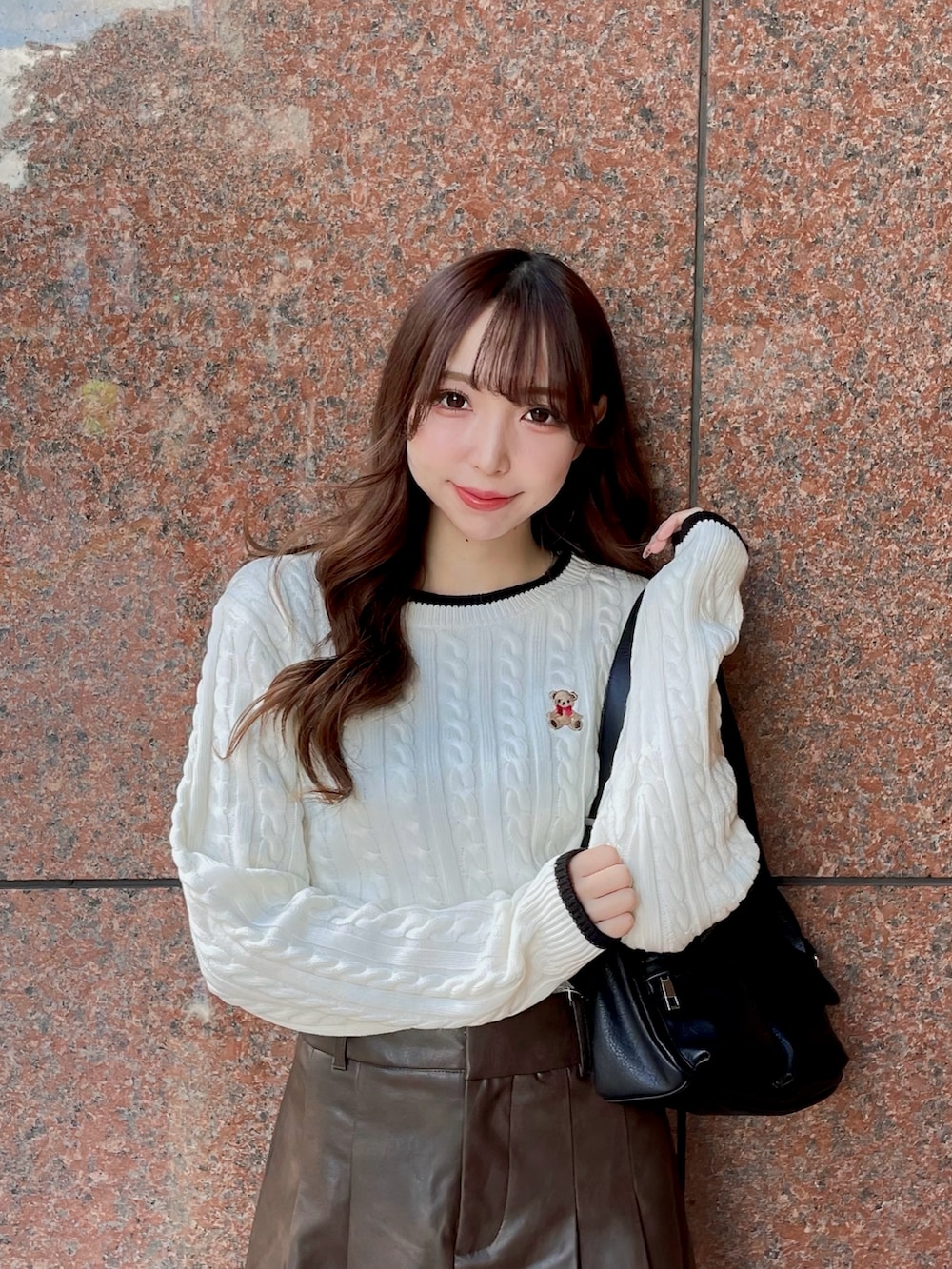 ホワイト系のニット/セーター、ブラック系のハンドバッグ、ブラウン系のスカートを着用したレディースの秋コーディネートの3枚目の写真