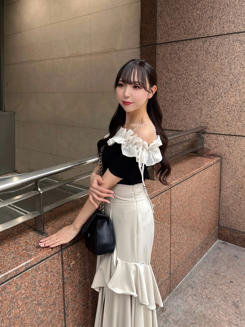 ブラック系のニット/セーター、ベージュ系のスカート、ブラック系のショルダーバッグを着用したレディースの夏コーディネートの7枚目の写真