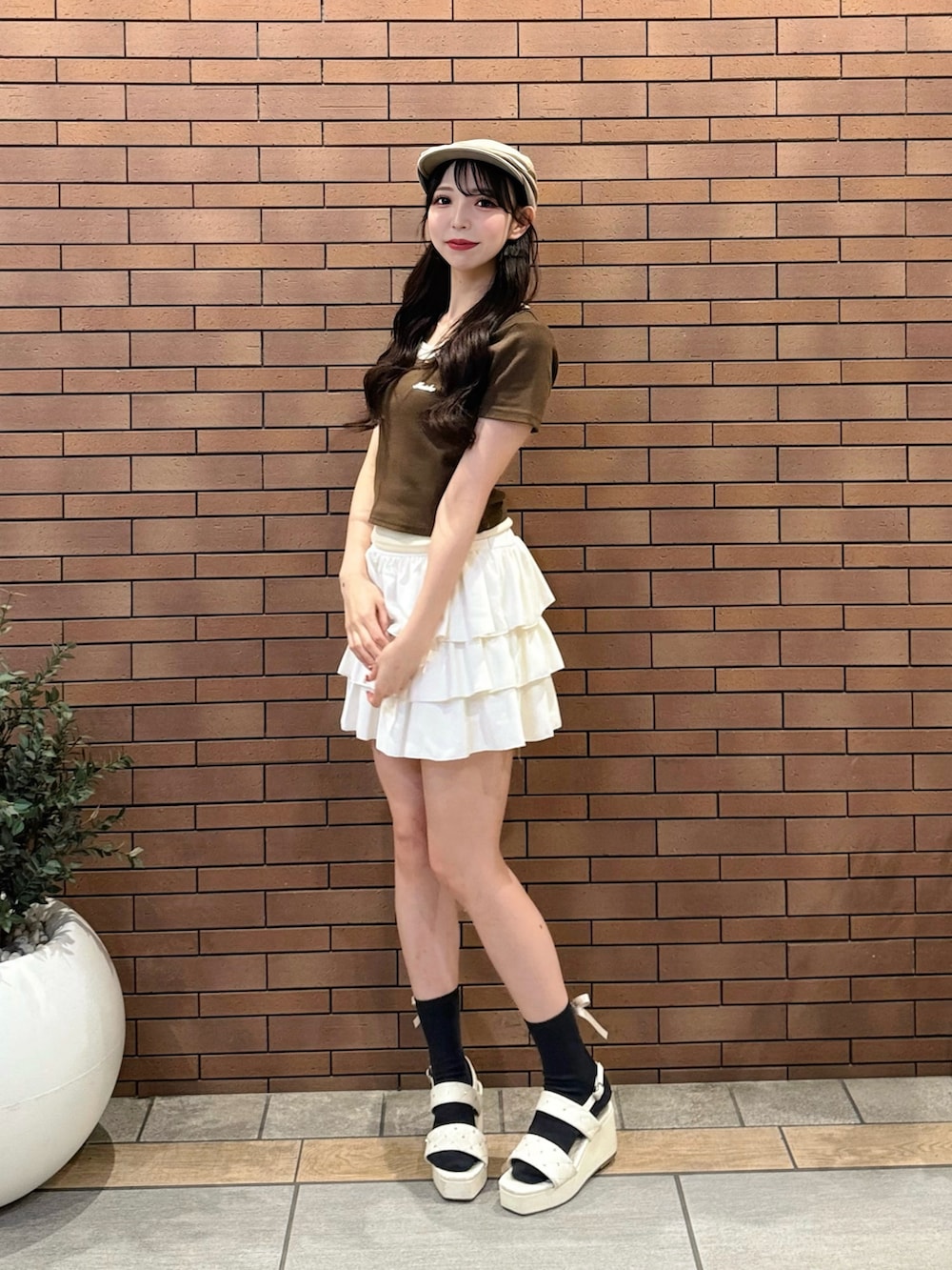 ブラウン系のTシャツ/カットソー、ホワイト系のスカート、ホワイト系のサンダルを着用したレディースの夏コーディネートの3枚目の写真