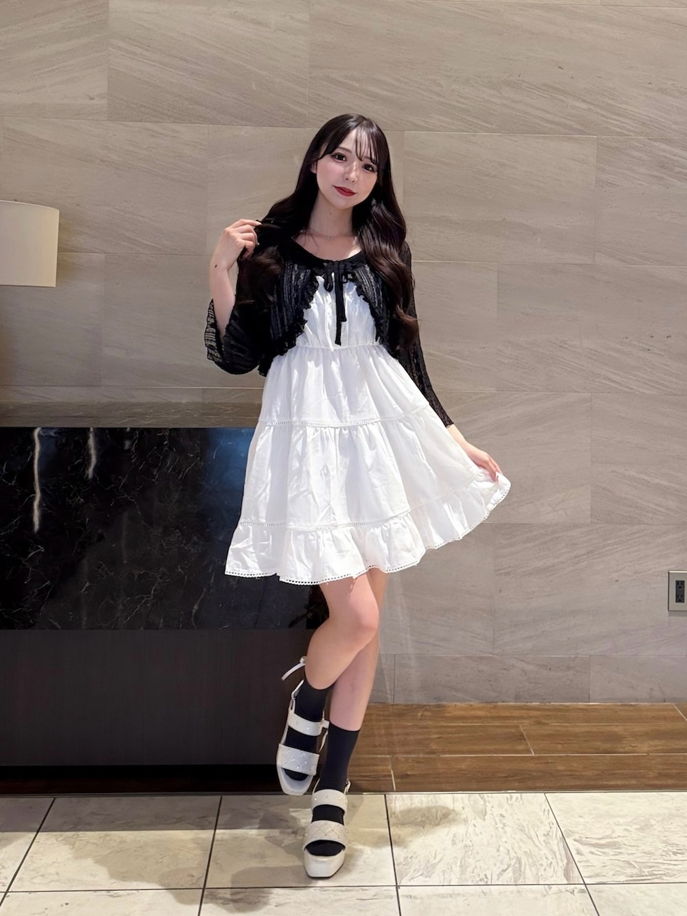 ホワイト系のワンピース、ブラック系のカーディガン/ボレロ、ホワイト系のサンダルを着用したレディースの夏コーディネートの2枚目の写真