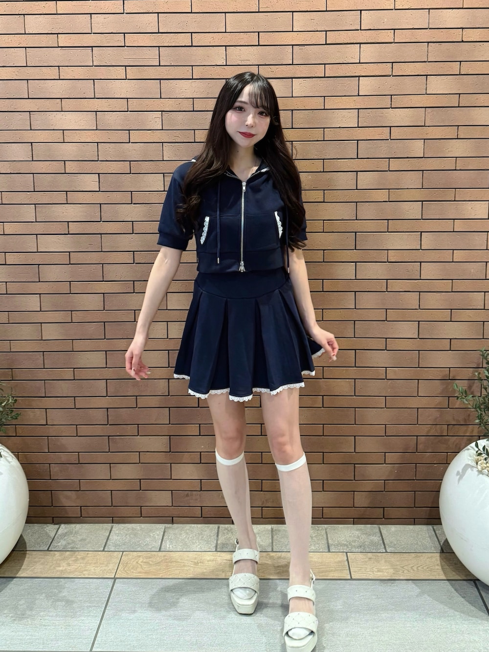 ブルー系のスカート、ブルー系のパーカー、ホワイト系のサンダルを着用したレディースの夏コーディネートの2枚目の写真