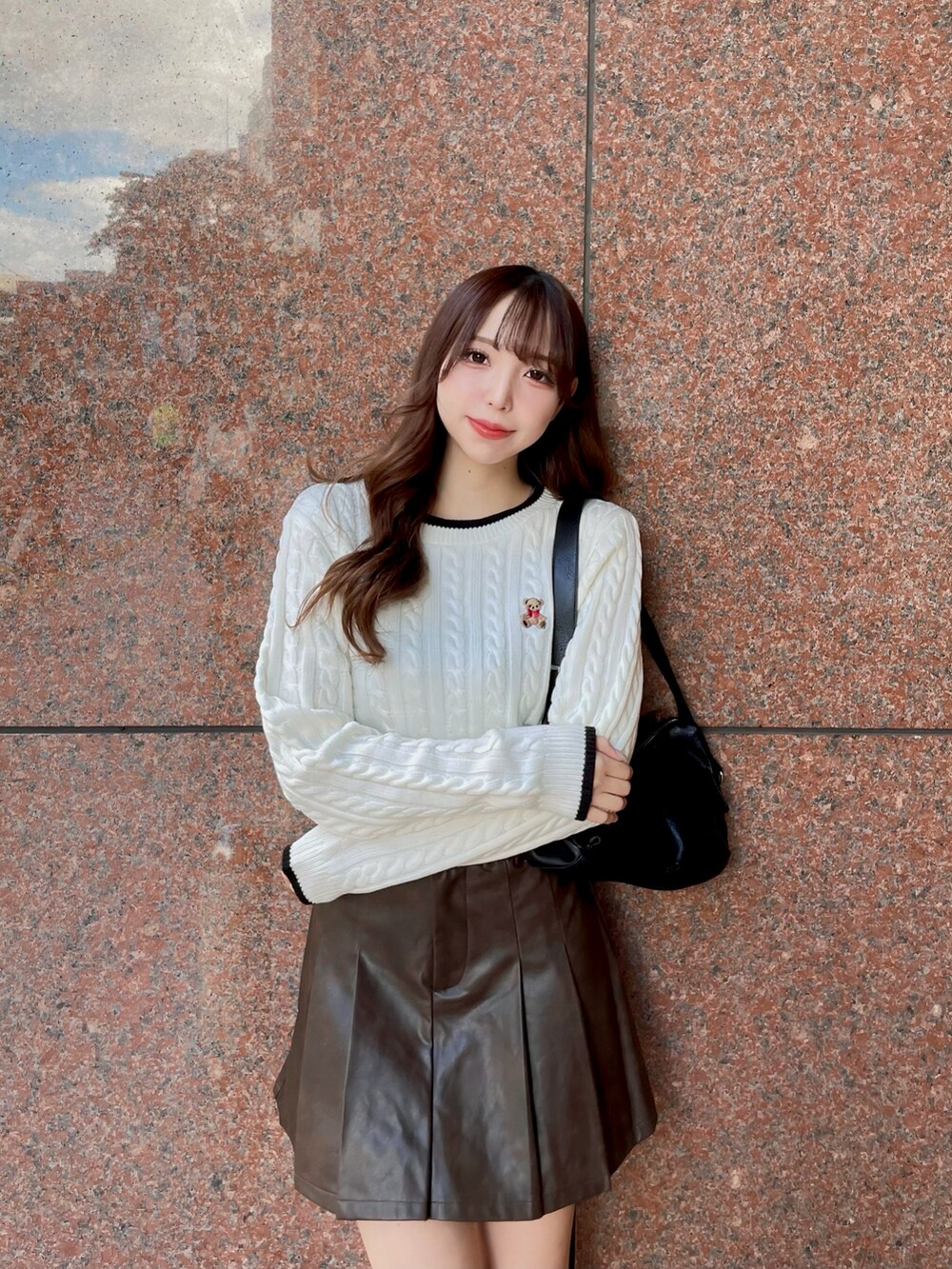 ホワイト系のニット/セーター、ブラック系のハンドバッグ、ブラウン系のスカートを着用したレディースの秋コーディネートの2枚目の写真