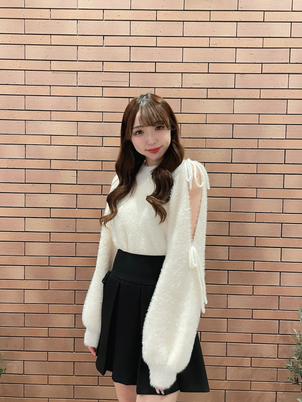 ホワイト系のニット/セーター、ブラック系のスカートを着用したレディースの秋コーディネートの2枚目の写真