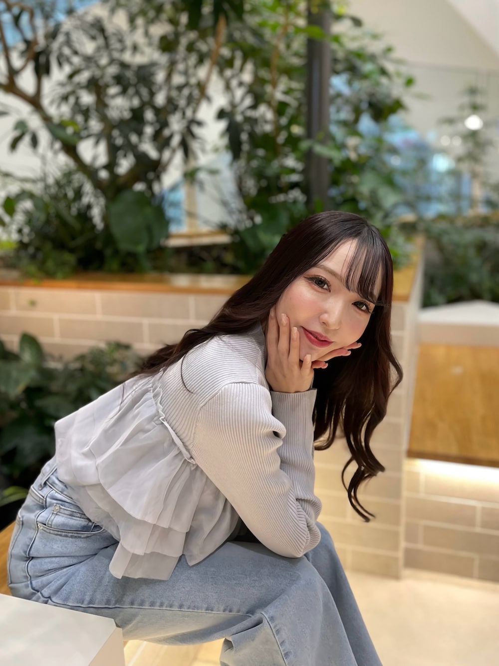 グレー系のニット/セーター、ブルー系のデニムパンツ、ブラック系のハンドバッグを着用したレディースの春コーディネートの3枚目の写真