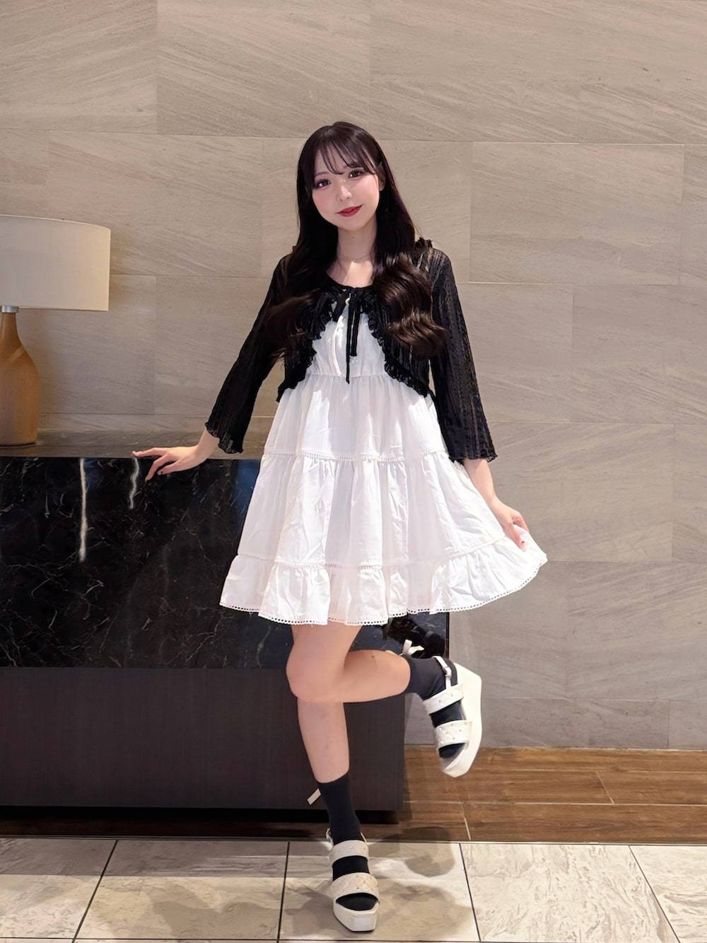 ホワイト系のワンピース、ブラック系のカーディガン/ボレロ、ホワイト系のサンダルを着用したレディースの夏コーディネートの3枚目の写真