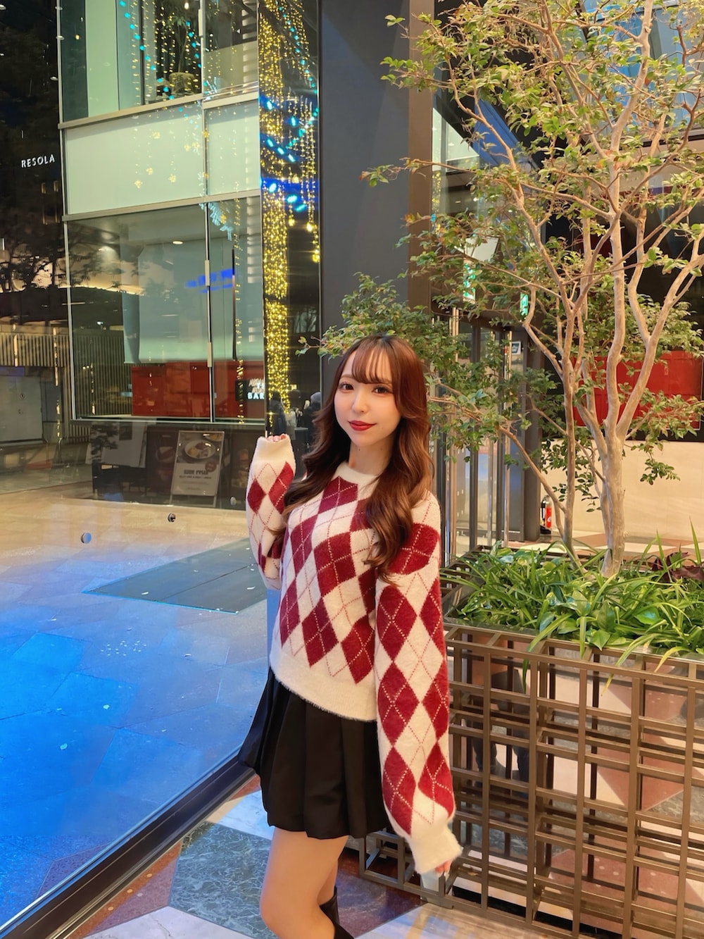 レッド系のニット/セーター、ブラック系のスカートを着用したレディースの冬コーディネートの2枚目の写真