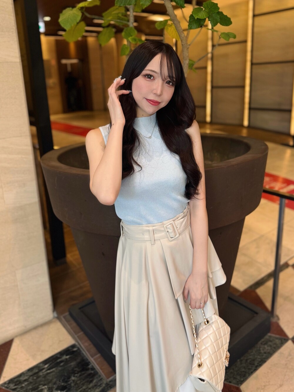 ベージュ系のスカート、ブルー系のニット/セーター、ホワイト系のショルダーバッグを着用したレディースの夏コーディネートの5枚目の写真