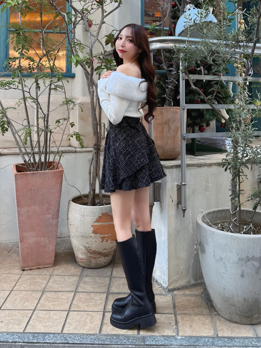 ブラック系のブーツ、ブラック系のショルダーバッグ、ブラック系のスカートを着用したレディースの秋コーディネートの2枚目の写真