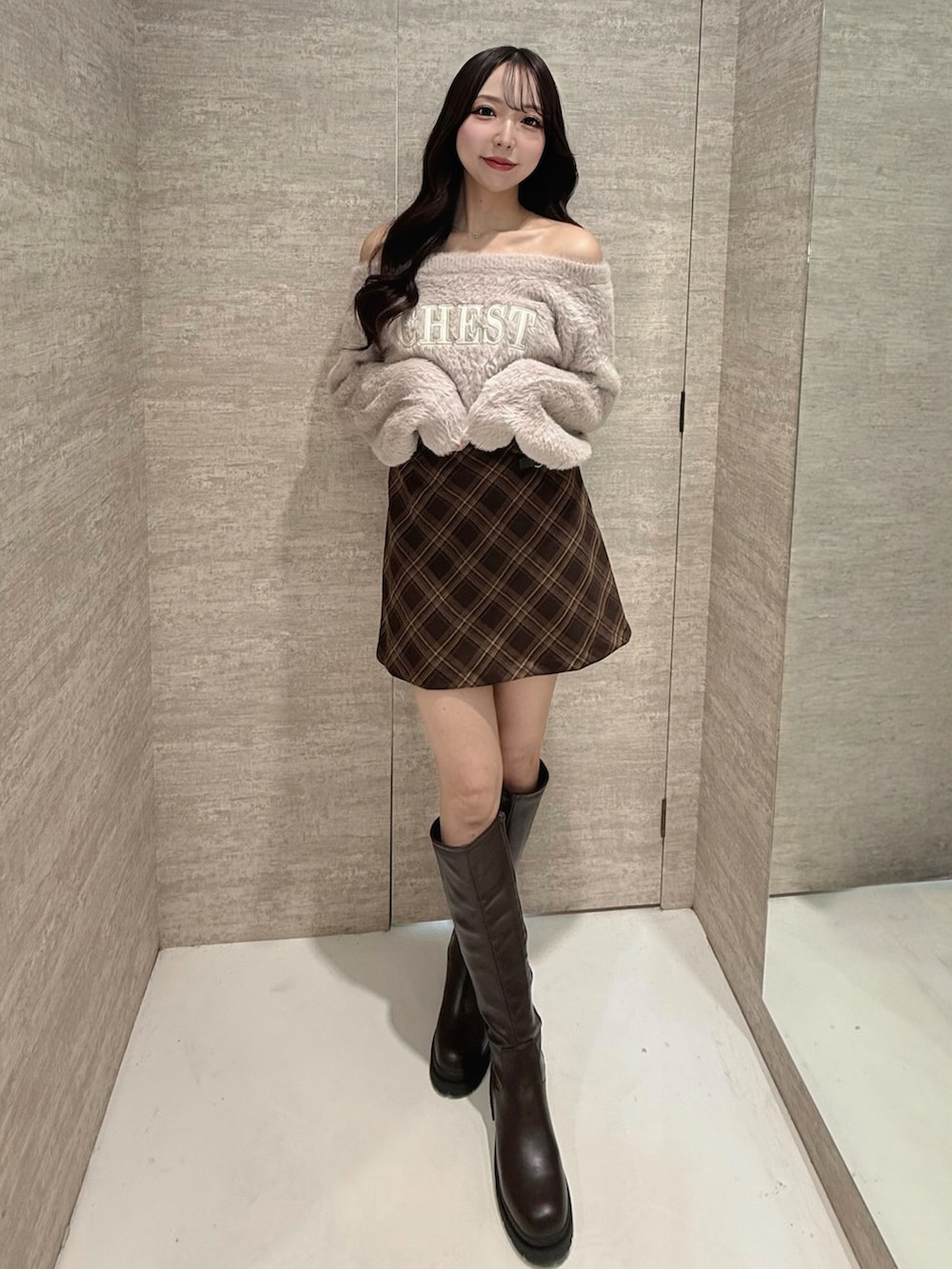 ピンク系のニット/セーター、ブラウン系のスカート、ブラウン系のブーツを着用したレディースの秋コーディネートの2枚目の写真