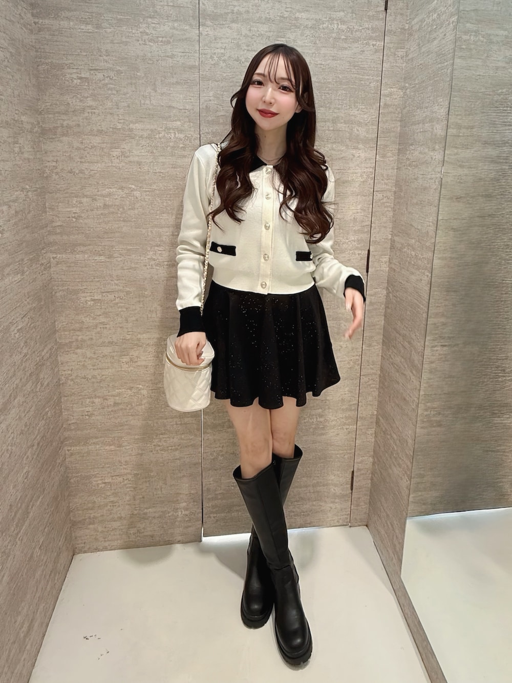 ホワイト系のカーディガン/ボレロ、ブラック系のスカート、ホワイト系のショルダーバッグを着用したレディースの春コーディネートの2枚目の写真