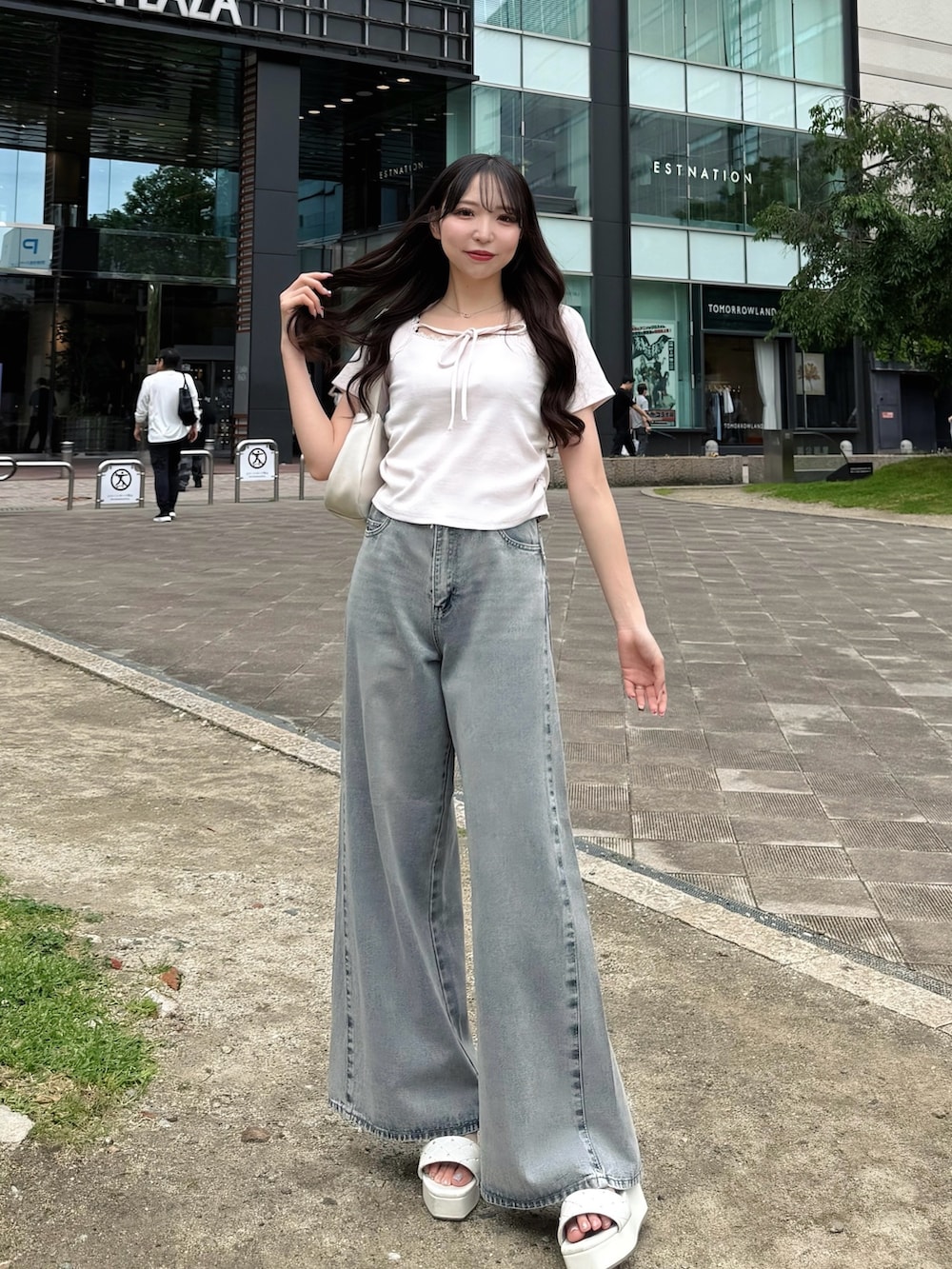 ブルー系のデニムパンツ、ピンク系のTシャツ/カットソー、ホワイト系のハンドバッグを着用したレディースの夏コーディネートの2枚目の写真