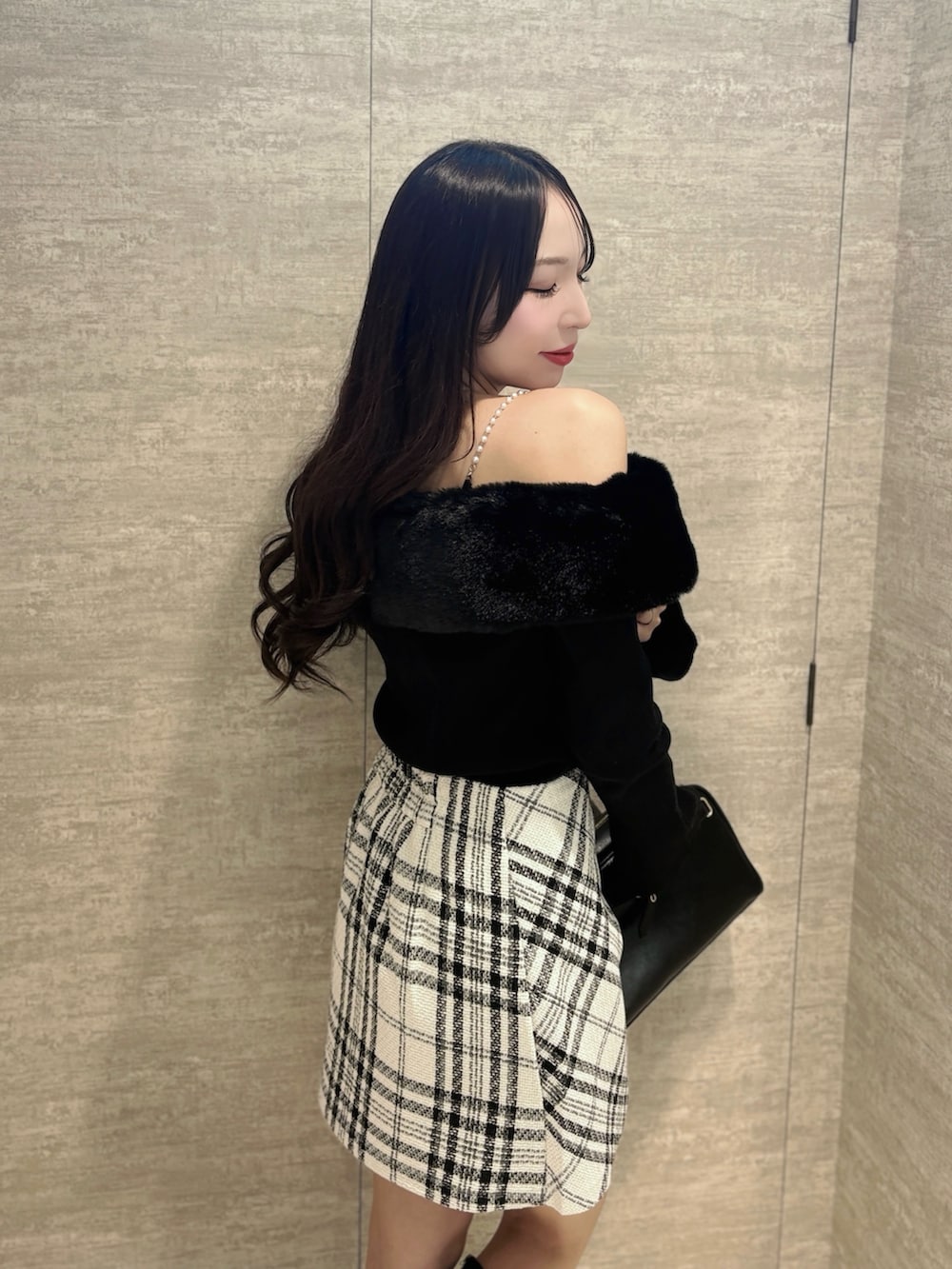 ブラック系のニット/セーター、ホワイト系のスカート、ブラック系のハンドバッグを着用したレディースの秋コーディネートの5枚目の写真