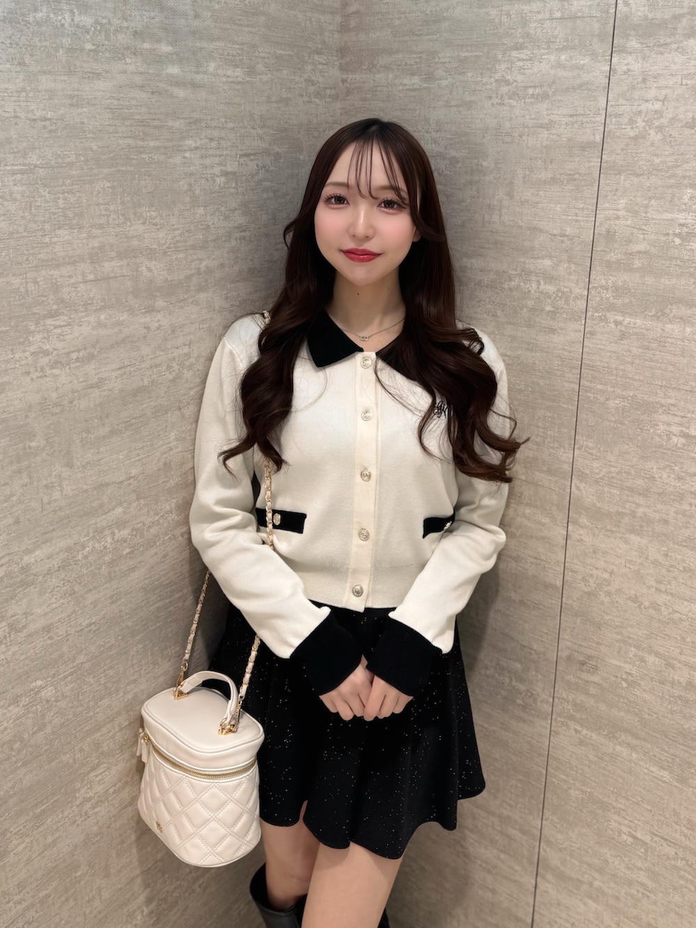 ホワイト系のカーディガン/ボレロ、ブラック系のスカート、ホワイト系のショルダーバッグを着用したレディースの春コーディネートの4枚目の写真