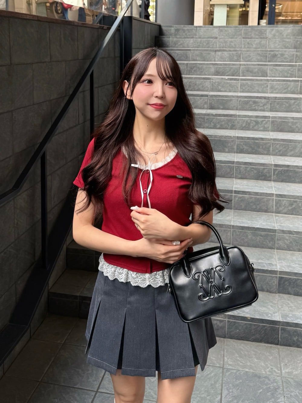 レッド系のTシャツ/カットソー、グレー系のスカート、ブラック系のハンドバッグを着用したレディースの夏コーディネートの5枚目の写真