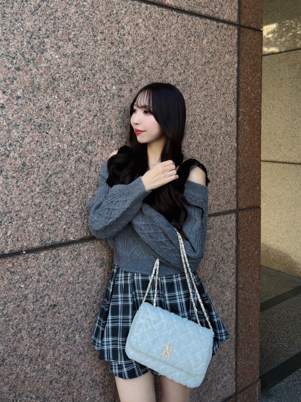 グレー系のニット/セーター、ホワイト系のショルダーバッグ、ブラック系のスカートを着用したレディースの秋コーディネートの5枚目の写真