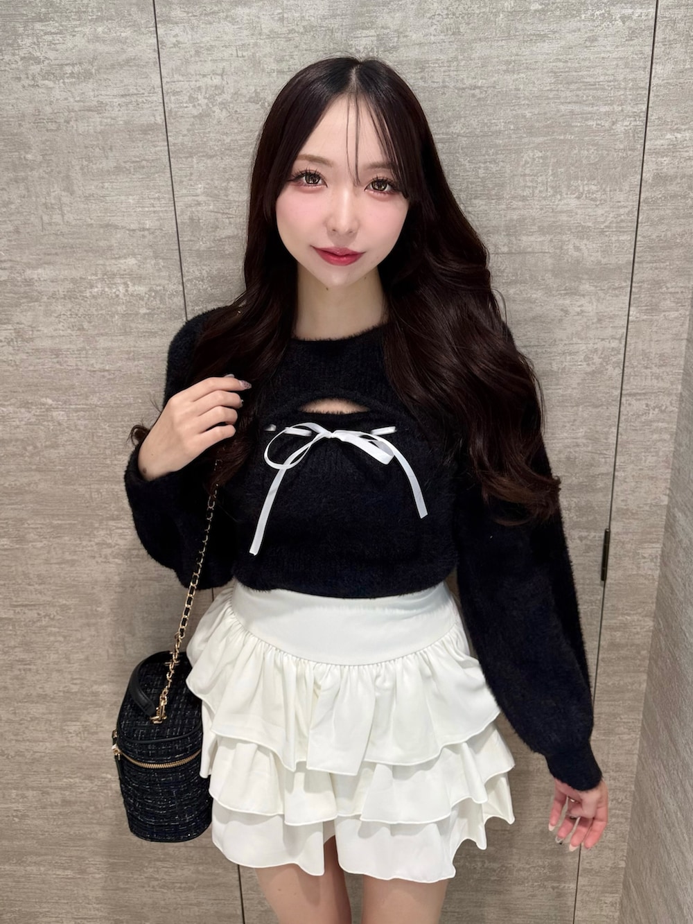 ブラック系のニット/セーター、ホワイト系のスカート、ブラック系のショルダーバッグを着用したレディースの秋コーディネートの5枚目の写真