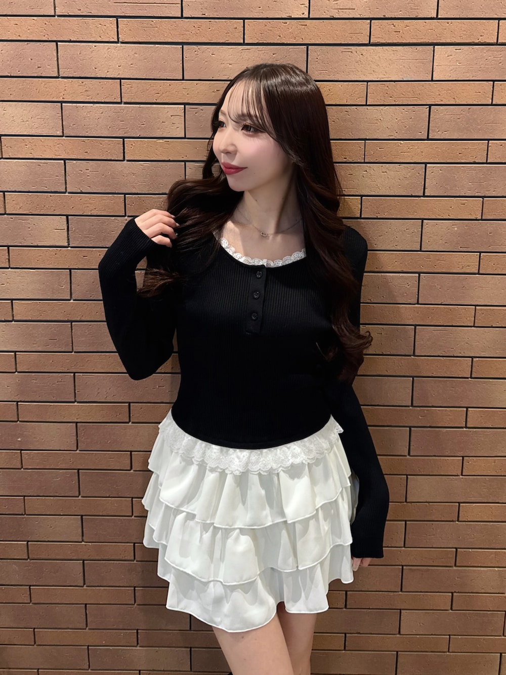 ブラック系のニット/セーター、ホワイト系のスカートを着用したレディースの冬コーディネートの2枚目の写真