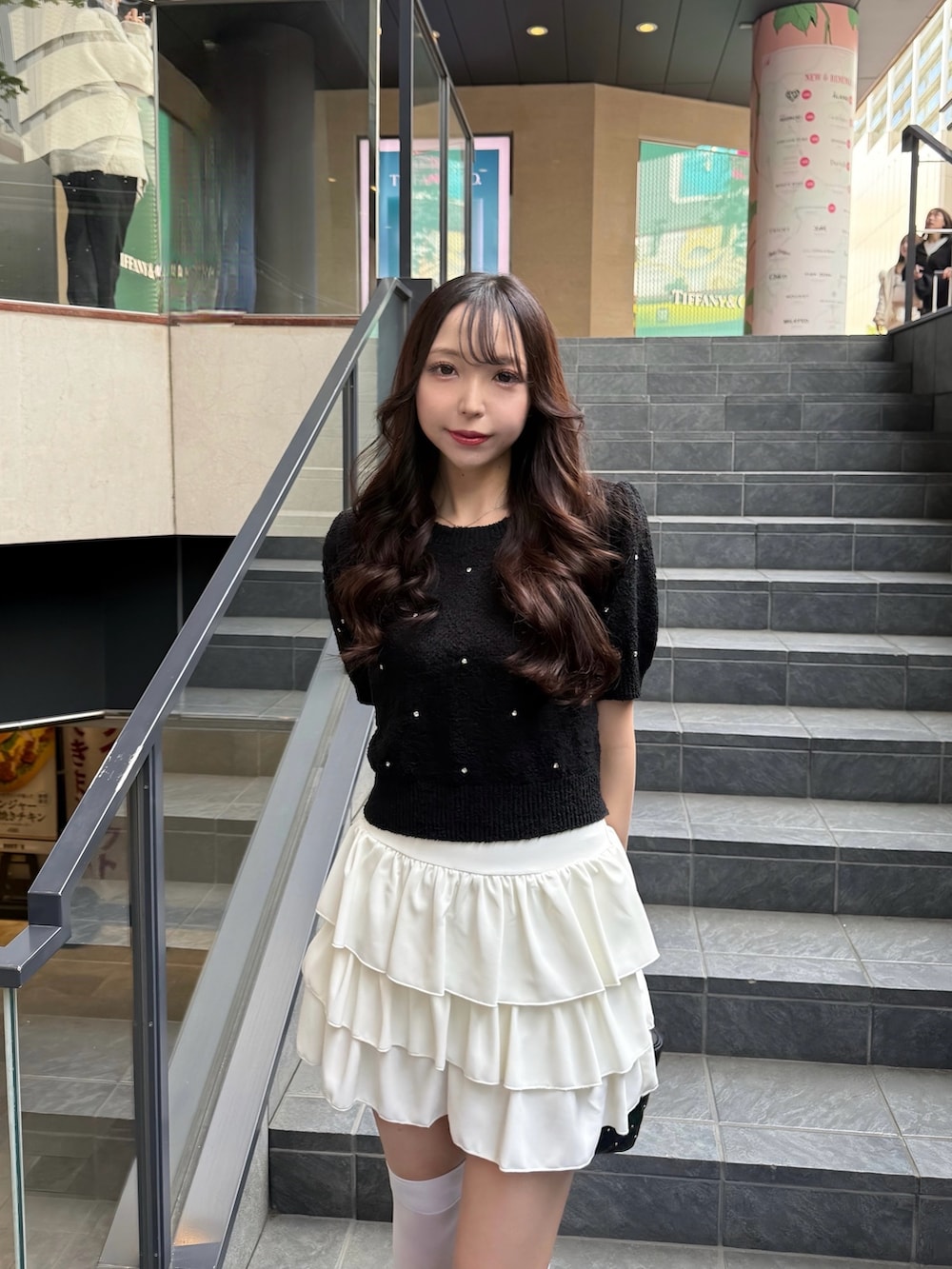 ブラック系のニット/セーター、ホワイト系のスカート、ブラック系のショルダーバッグを着用したレディースの春コーディネートの3枚目の写真