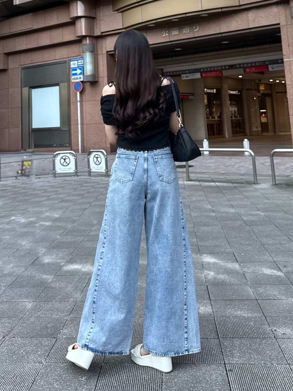 ブルー系のデニムパンツ、ブラック系のTシャツ/カットソー、ホワイト系のサンダルを着用したレディースの夏コーディネートの3枚目の写真