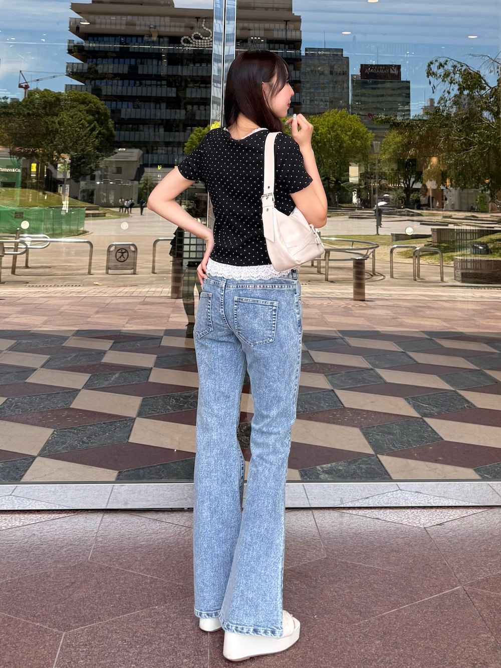 ブルー系のデニムパンツ、ホワイト系のサンダル、ホワイト系のハンドバッグを着用したレディースの夏コーディネートの3枚目の写真