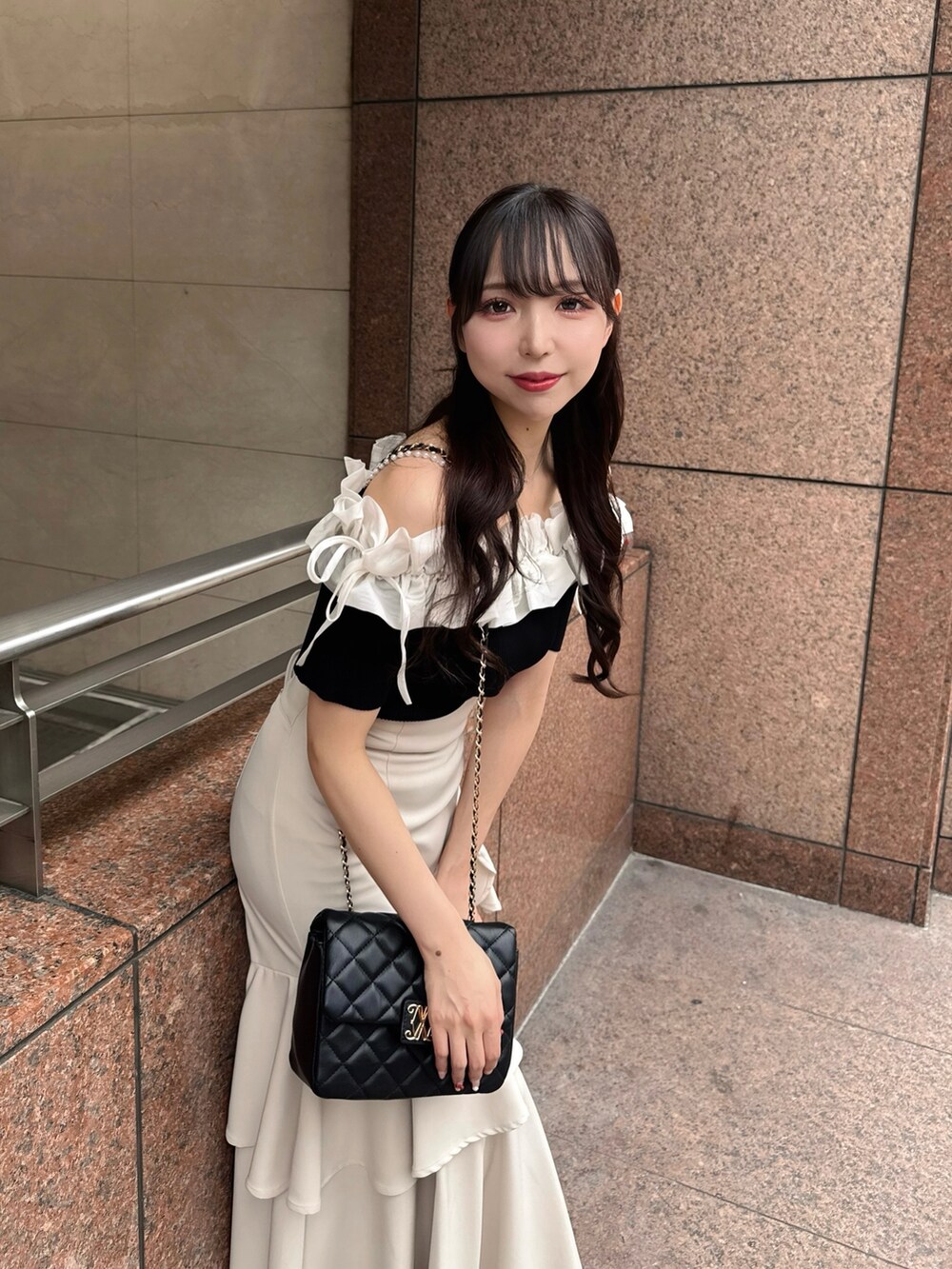 ブラック系のニット/セーター、ベージュ系のスカート、ブラック系のショルダーバッグを着用したレディースの夏コーディネートの9枚目の写真