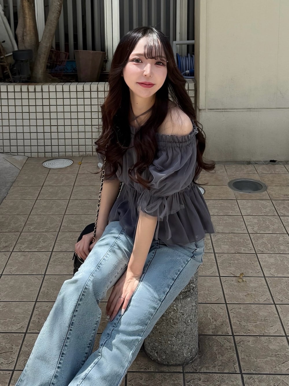 グレー系のシャツ/ブラウス、ブルー系のデニムパンツ、ブラック系のショルダーバッグを着用したレディースの春コーディネートの4枚目の写真