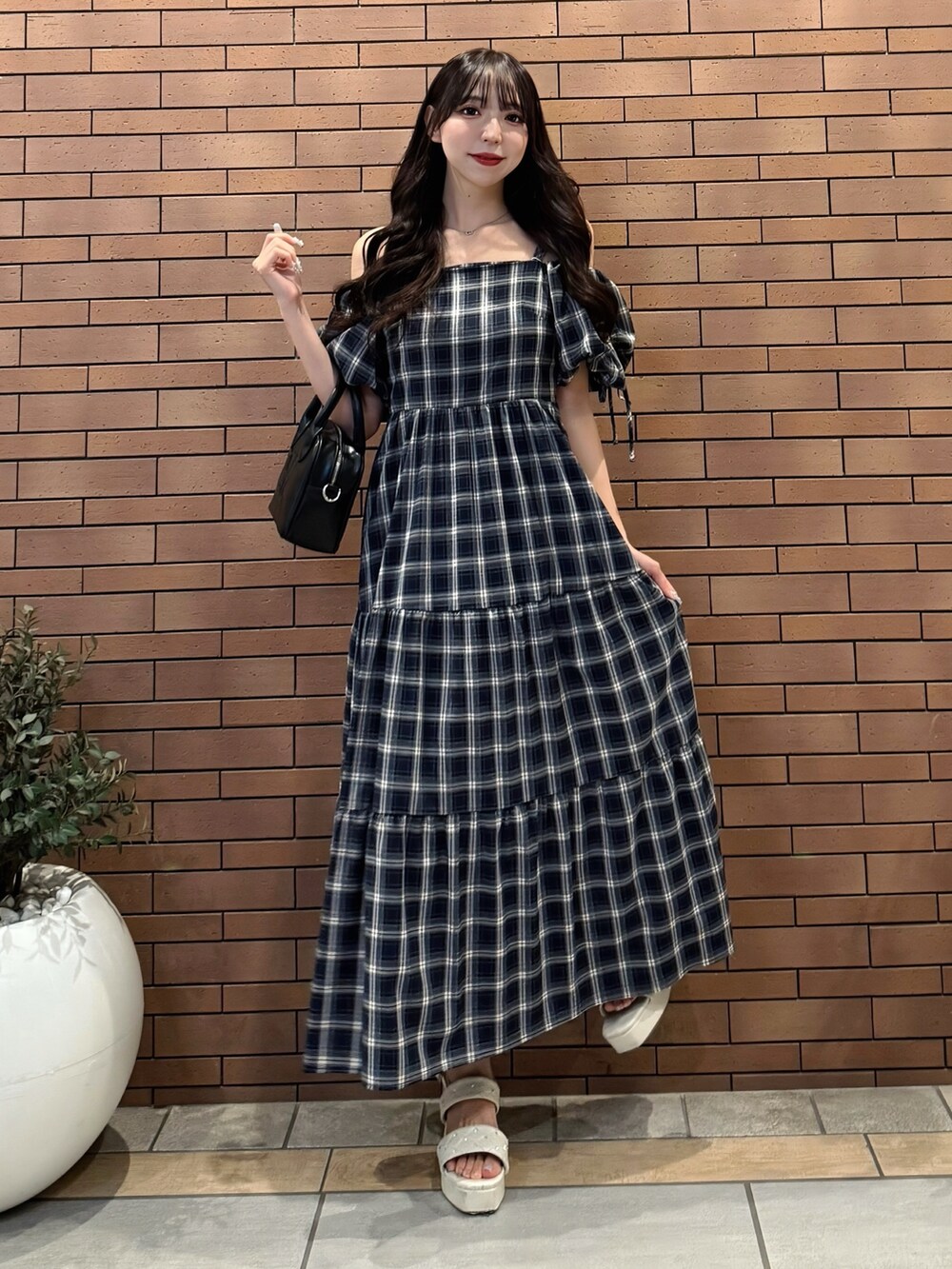 ブルー系のワンピース、ブラック系のハンドバッグ、ホワイト系のサンダルを着用したレディースの夏コーディネートの5枚目の写真