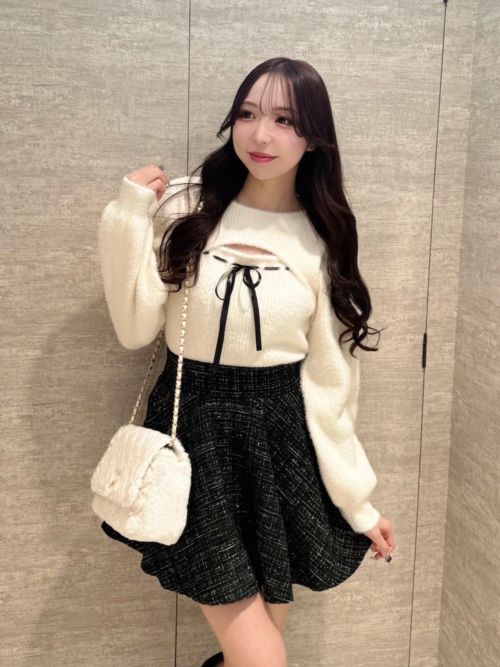 ホワイト系のニット/セーター、ブラック系のスカート、ホワイト系のショルダーバッグを着用したレディースの秋コーディネートの2枚目の写真