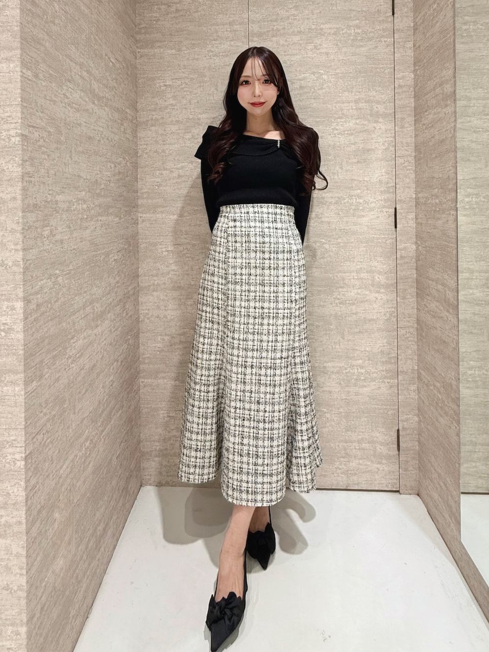 ブラック系のニット/セーター、ホワイト系のスカートを着用したレディースの秋コーディネートの2枚目の写真