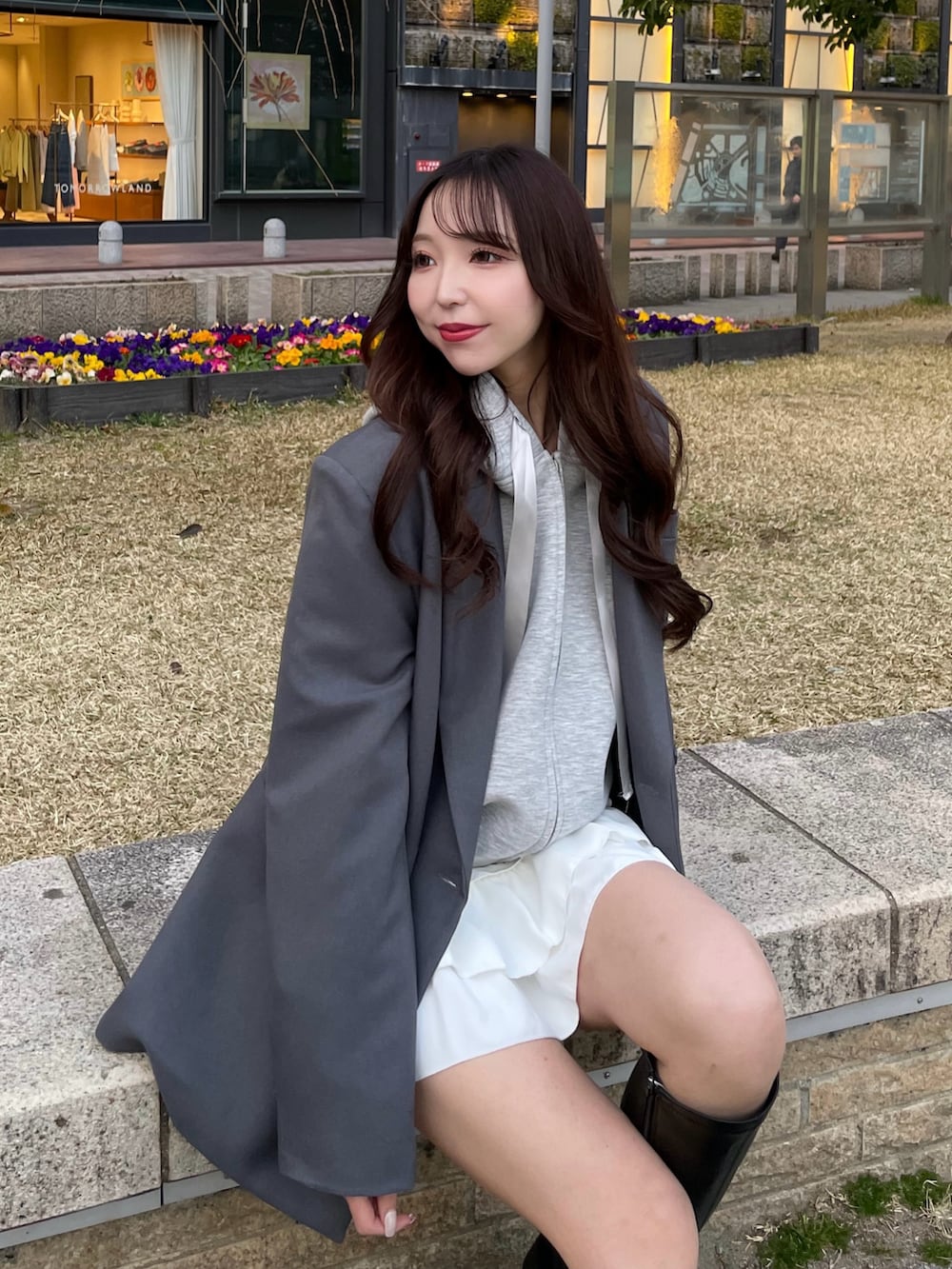 グレー系のパーカー、グレー系のテーラードジャケット、ホワイト系のスカートを着用したレディースの春コーディネートの2枚目の写真