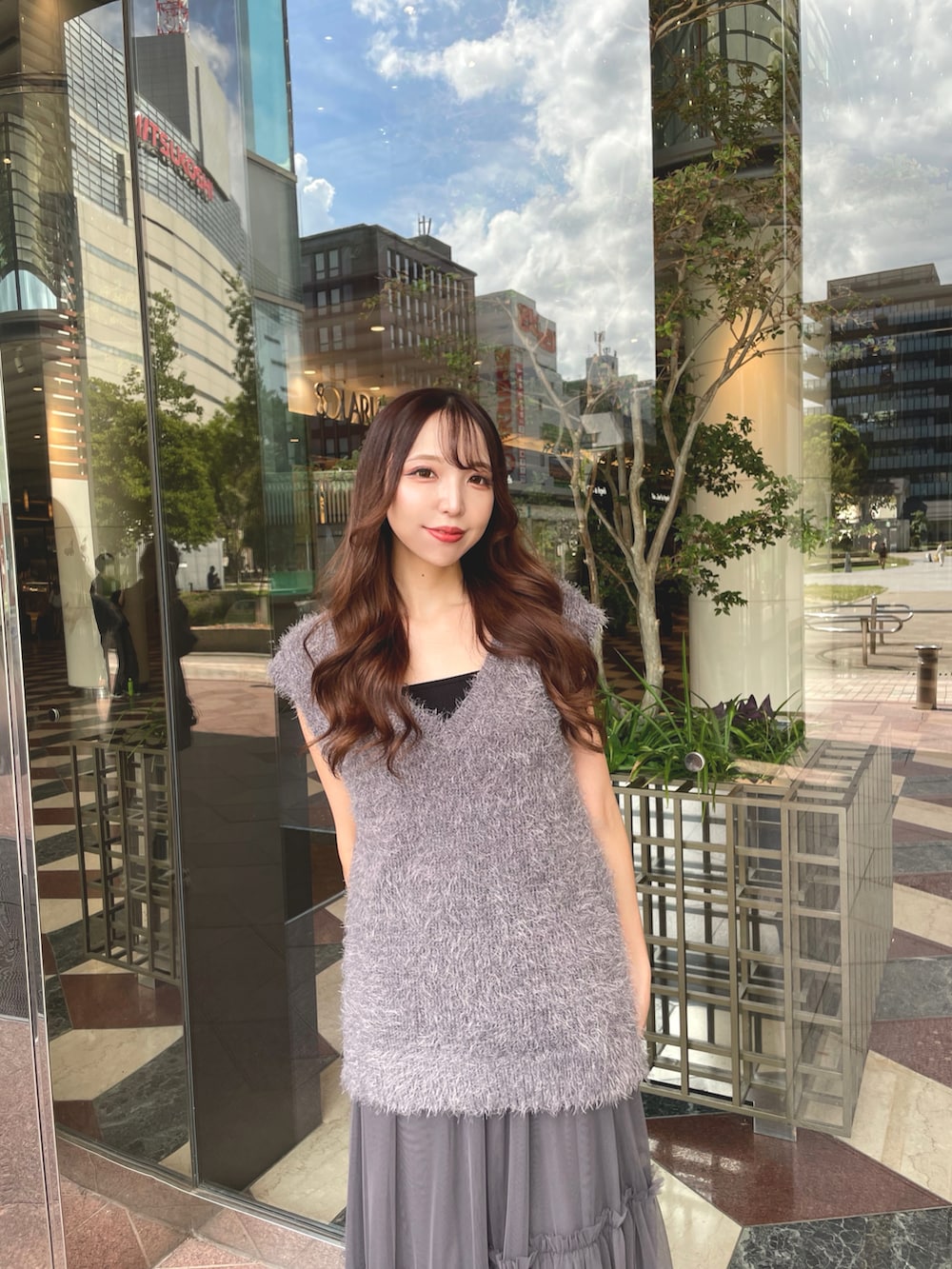 グレー系のベスト、グレー系のスカートを着用したレディースの秋コーディネートの2枚目の写真