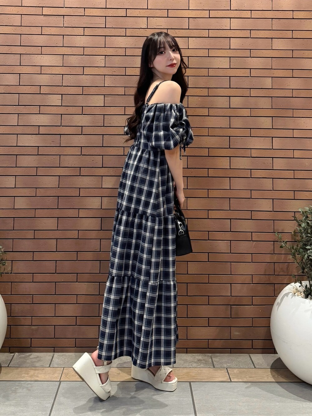 ブルー系のワンピース、ブラック系のハンドバッグ、ホワイト系のサンダルを着用したレディースの夏コーディネートの2枚目の写真