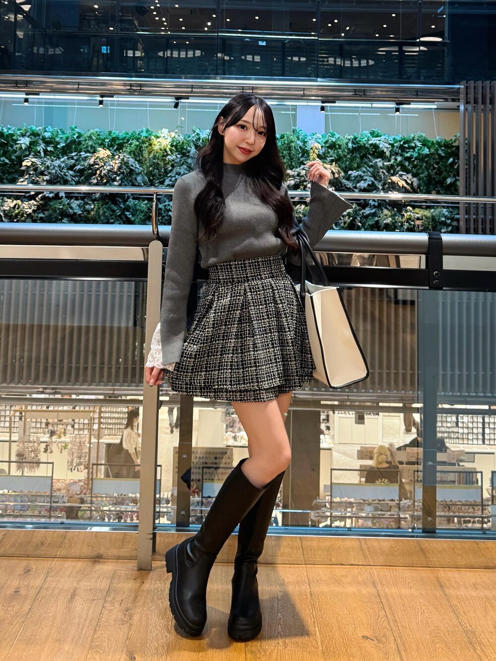 ホワイト系のトートバッグ、ブラック系のブーツ、ブラック系のスカートを着用したレディースの秋コーディネートの2枚目の写真