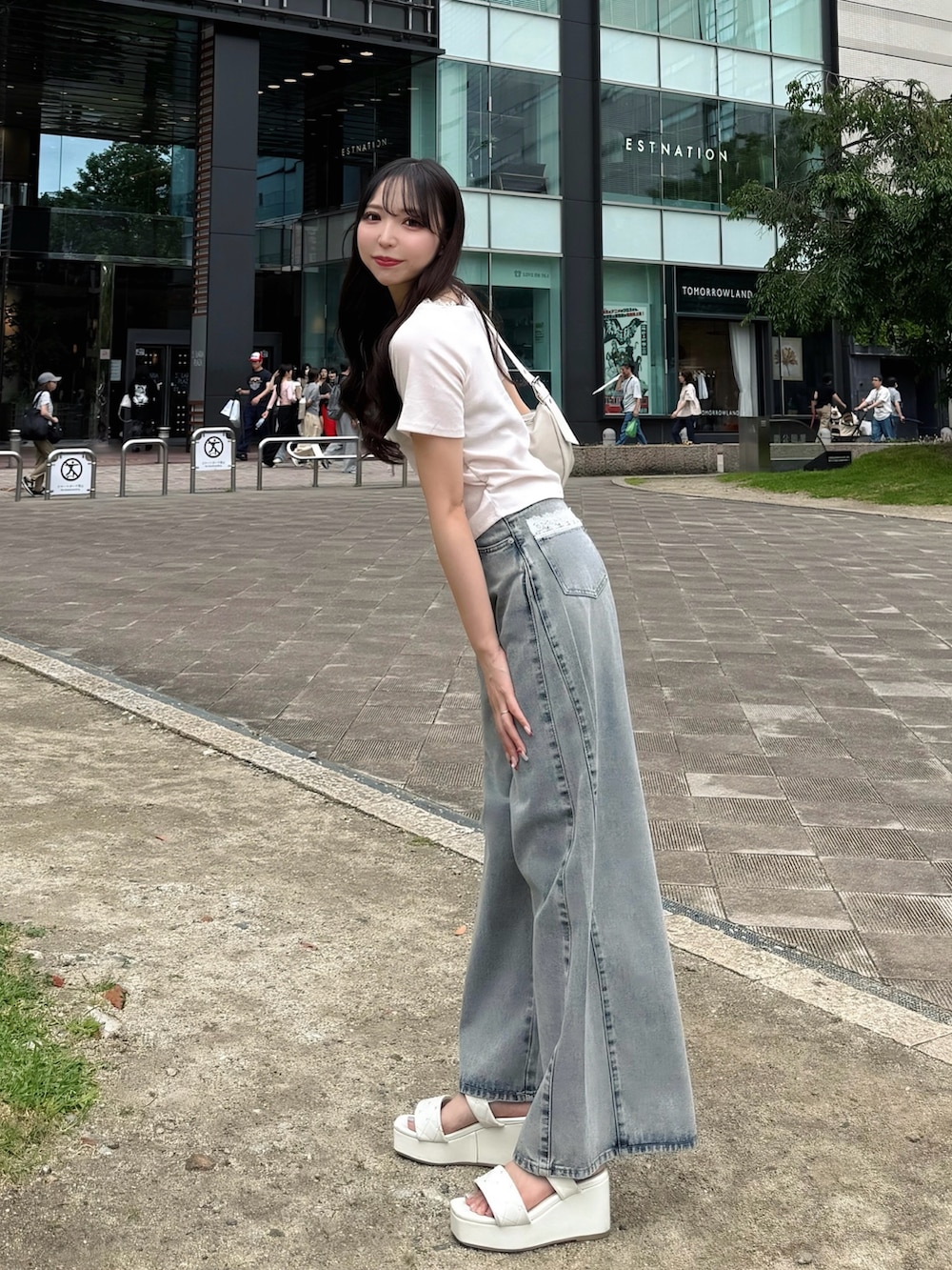 ブルー系のデニムパンツ、ピンク系のTシャツ/カットソー、ホワイト系のハンドバッグを着用したレディースの夏コーディネートの3枚目の写真