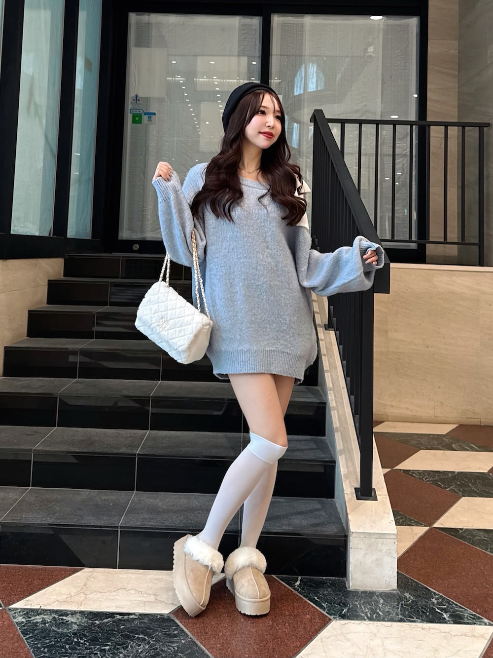 ブルー系のチュニック、ベージュ系のブーツ、ホワイト系のショルダーバッグを着用したレディースの冬コーディネートの4枚目の写真