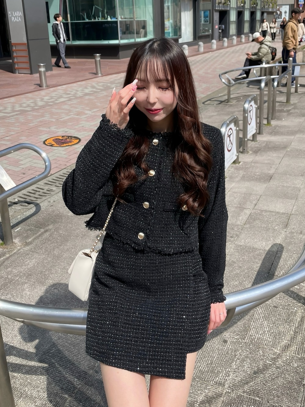 ブラック系のノーカラージャケット、ホワイト系のショルダーバッグ、ブラック系のスカートを着用したレディースの春コーディネートの2枚目の写真