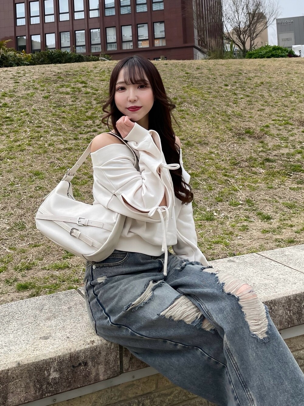 ホワイト系のスウェット、ホワイト系のハンドバッグ、ブルー系のデニムパンツを着用したレディースの春コーディネートの2枚目の写真