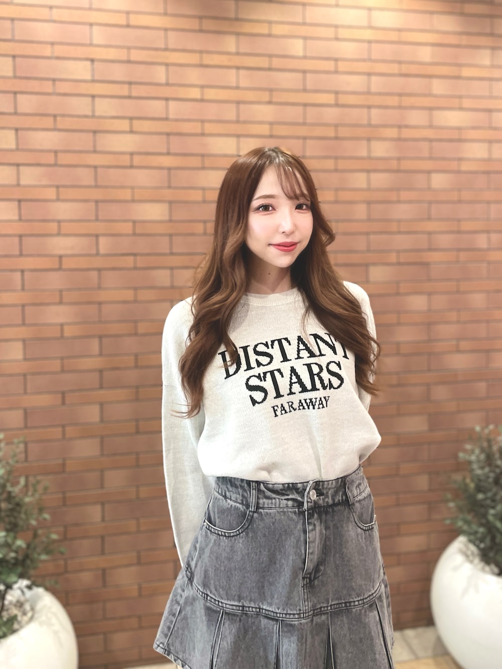 ホワイト系のニット/セーター、グレー系のデニムスカート、ベージュ系のブーツを着用したレディースの秋コーディネートの2枚目の写真