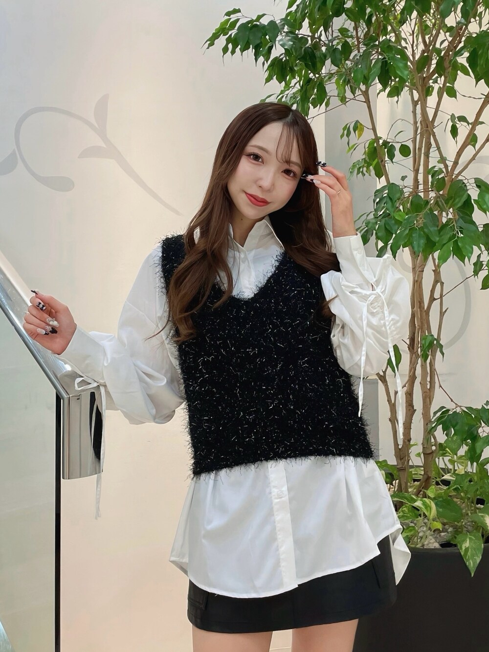 ブラック系のニット/セーター、ホワイト系のシャツ/ブラウス、ブラック系のスカートを着用したレディースの秋コーディネートの2枚目の写真