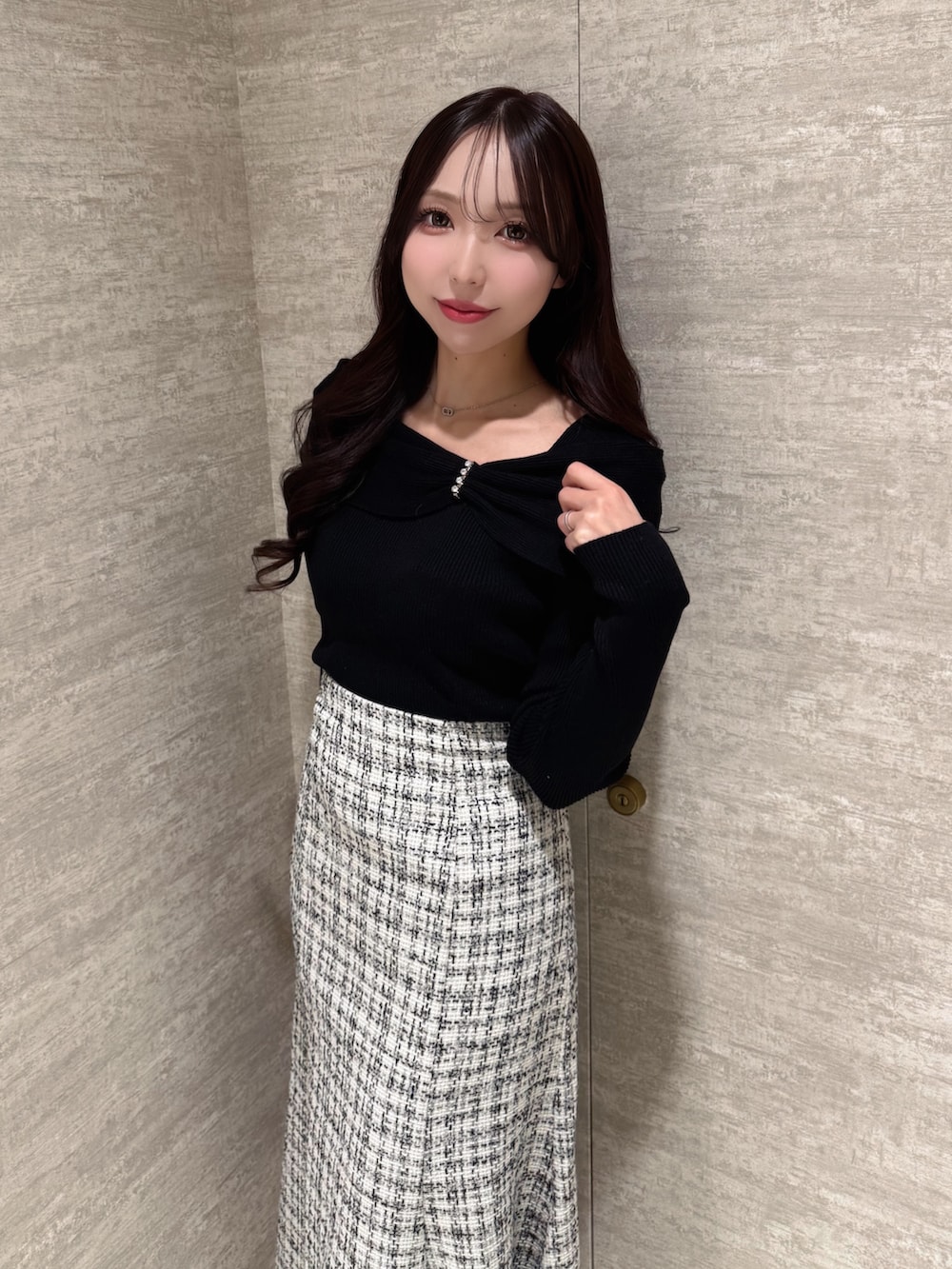 ブラック系のニット/セーター、ホワイト系のスカートを着用したレディースの秋コーディネートの4枚目の写真