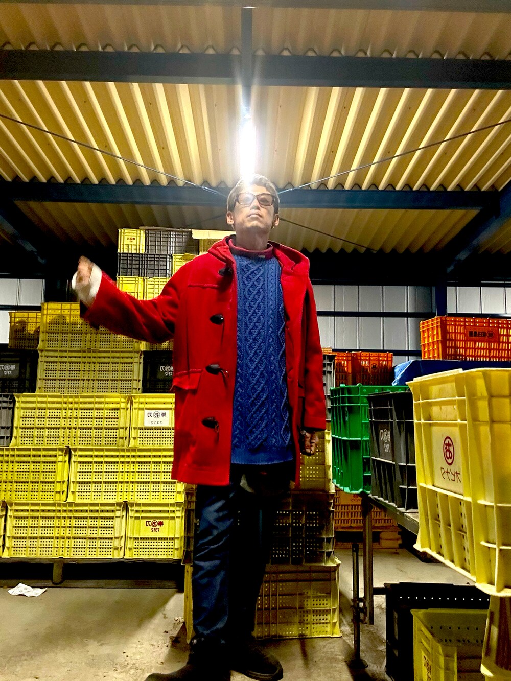 レッド系のダッフルコート、ブルー系のニット/セーター、ブルー系のデニムパンツを着用したメンズの秋コーディネートの2枚目の写真