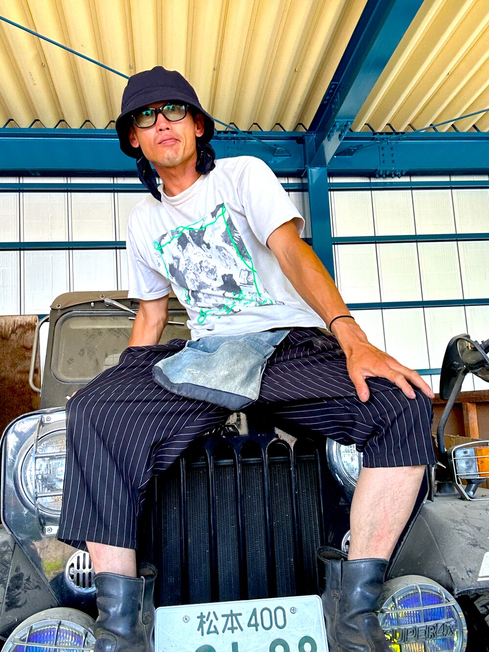 ブルー系のその他パンツ、グレー系のTシャツ/カットソー、ブラック系のブーツを着用したメンズの夏コーディネートの2枚目の写真